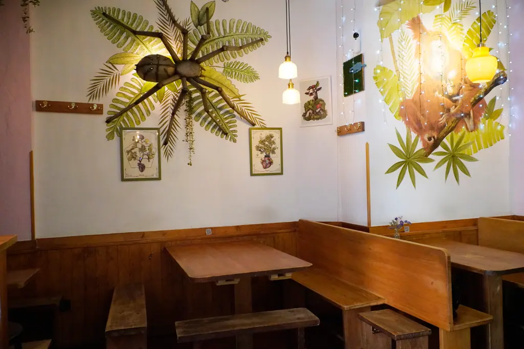 Comedor de Viva Chapata con bancos de madera, lámparas colgantes y un gran mural de selva en la pared