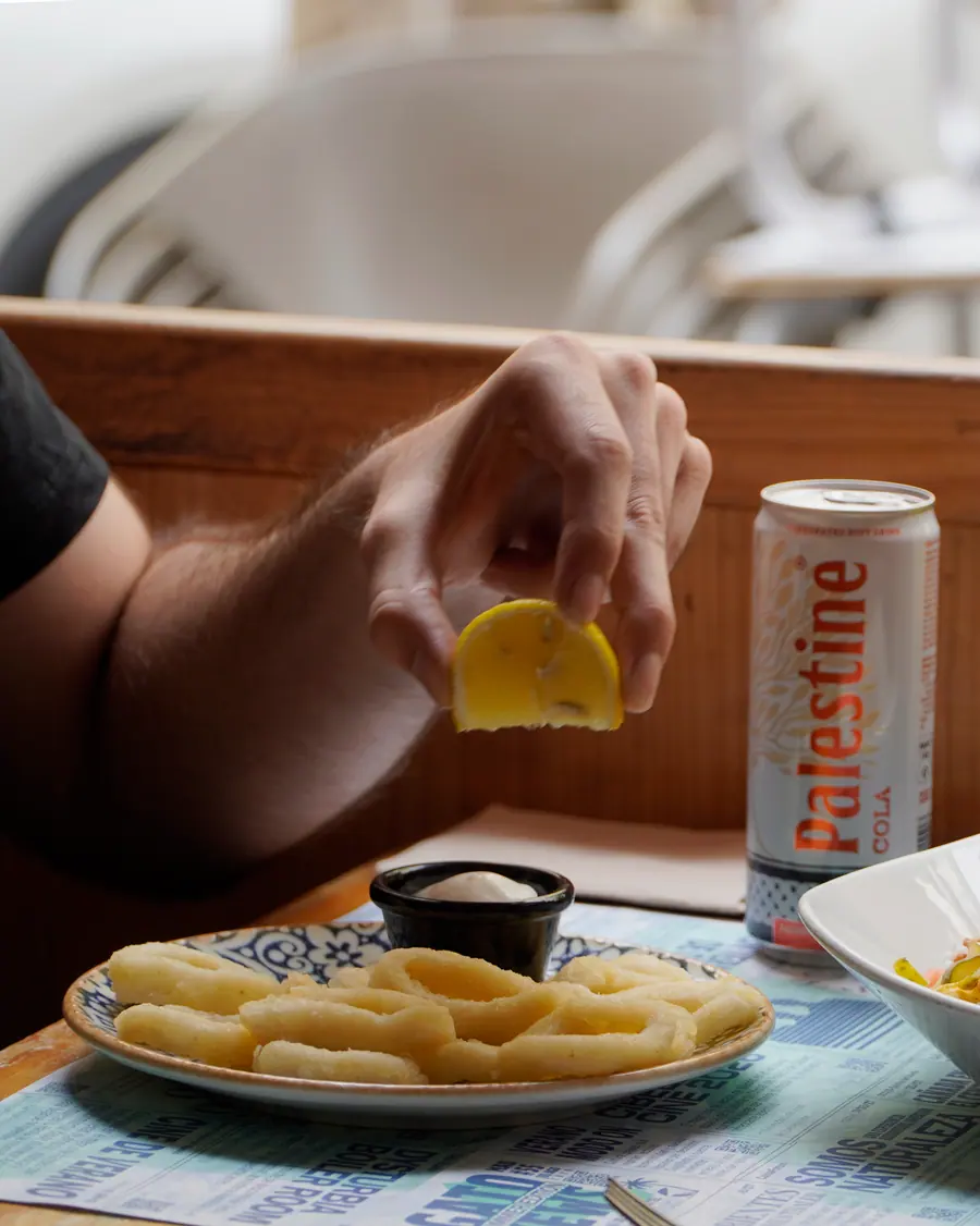Exprimiendo limón sobre unos «no calamares» con salsa en Viva Chapata, taberna vegana de Lavapiés